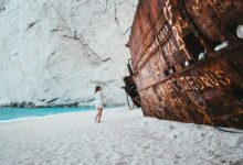woman standing near brown metal frame on seashore