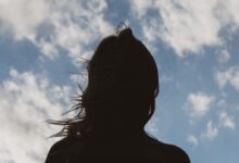 silhouette of woman under blue sky and white clouds during daytime