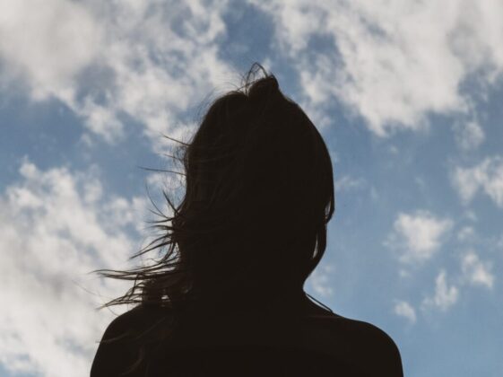 silhouette of woman under blue sky and white clouds during daytime