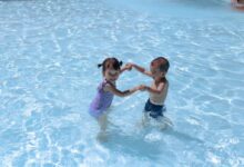 girl and boy playing in swimming pool during daytime