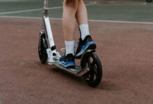 person in black and white nike sneakers riding blue and white skateboard during daytime