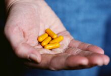 yellow medication pill on persons hand