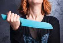 woman in black cardigan holding blue plastic hair comb