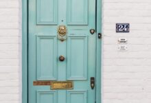 teal wooden door beside white concrete wall