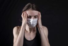 woman in black tank top covering her face with her hands