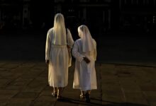 woman in white robe standing on brown brick floor during night time