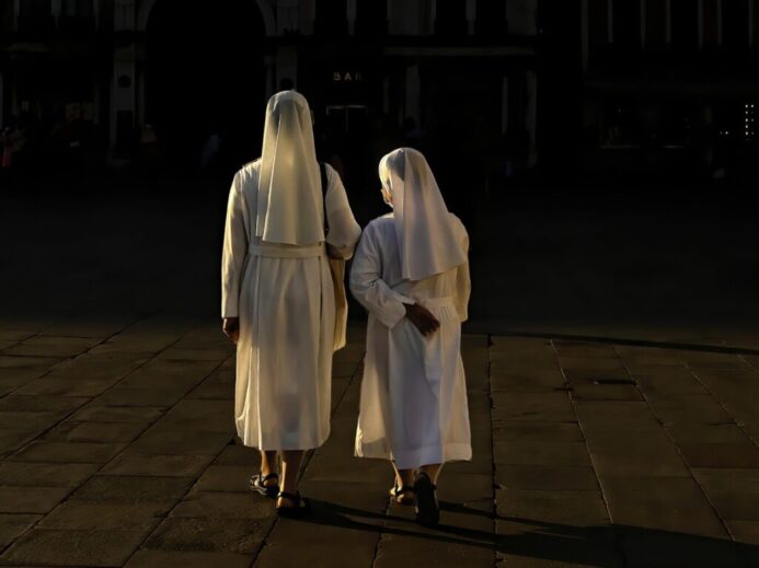 woman in white robe standing on brown brick floor during night time