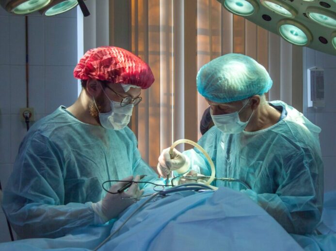 two men wearing blue lab coats