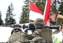 man in green and brown camouflage uniform holding black and red flag