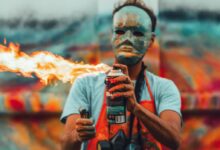 man in white crew neck t-shirt holding black and orange bottle