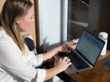 woman in white long sleeve shirt using black laptop computer