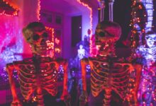 two skeleton near white concrete building with string lights at daytime