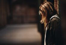 woman leaning against a wall in dim hallway
