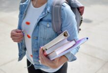 woman wearing blue denim jacket holding book