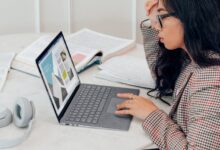 woman in red and white plaid dress shirt using microsoft surface laptop