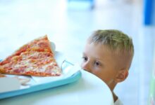baby in white shirt eating pizza