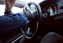man holding black steering wheel