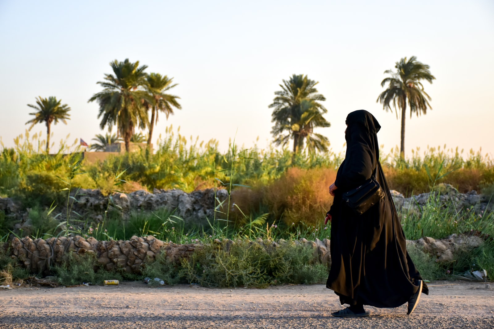 woman in black hijab standing on gray concrete road during daytime