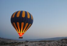 blue and yellow hot air balloon at top of high rise mountains