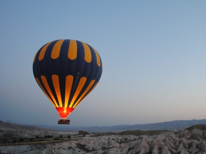 blue and yellow hot air balloon at top of high rise mountains