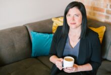 woman holding cup of coffee sitting on sofa
