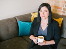 woman holding cup of coffee sitting on sofa