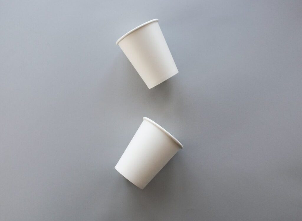 two white disposable cups on gray surface