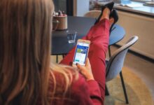 woman in red jacket holding white smartphone