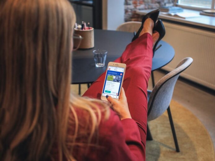 woman in red jacket holding white smartphone