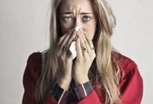 Photo of Crying Woman in Red Long Sleeve Shirt Blowing Her Nose