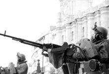 Grayscale Photo of Man Holding Rifle