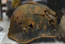 rusty soldier helmet with holes on white surface