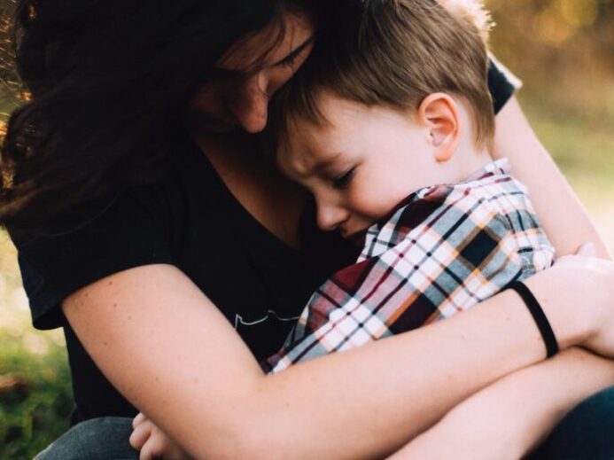 woman hugging boy on her lap