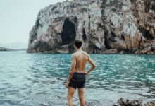 man in black shorts standing on rocky shore during daytime