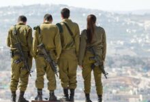 three men and one woman soldiers standing on rock during daytime