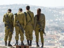 three men and one woman soldiers standing on rock during daytime