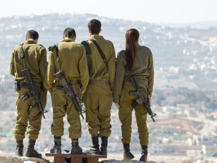 three men and one woman soldiers standing on rock during daytime