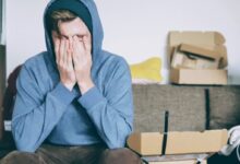 man covering face with both hands while sitting on bench
