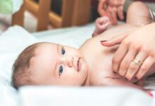 baby lying in white textile