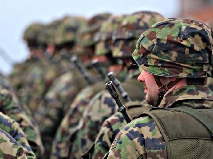 man in green and brown camouflage uniform holding black rifle