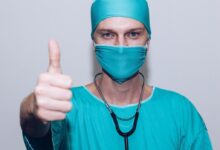 person in green crew neck long sleeve shirt wearing blue face mask