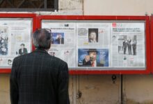 man reading newspaper in bulletin board