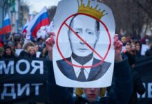 man in blue jacket holding white and red bird print banner