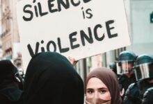 woman in black hijab holding white and black printed board
