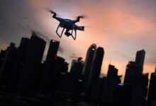 silhouette of quadcopter drone hovering near the city
