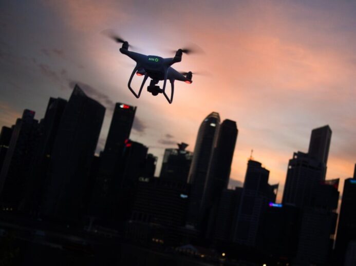 silhouette of quadcopter drone hovering near the city
