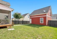 red and white wooden house on green grass field during daytime