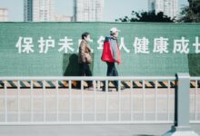 2 women standing on gray concrete road during daytime