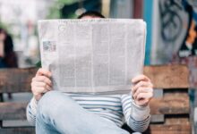 man sitting on bench reading newspaper