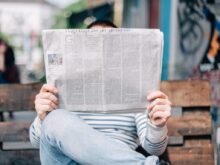 man sitting on bench reading newspaper